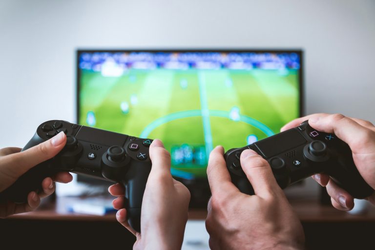 two people playing PlayStation football game - photo credit: jan vasek - siteunsplash - adplay - رسانه و تبلیغات - ادپلی